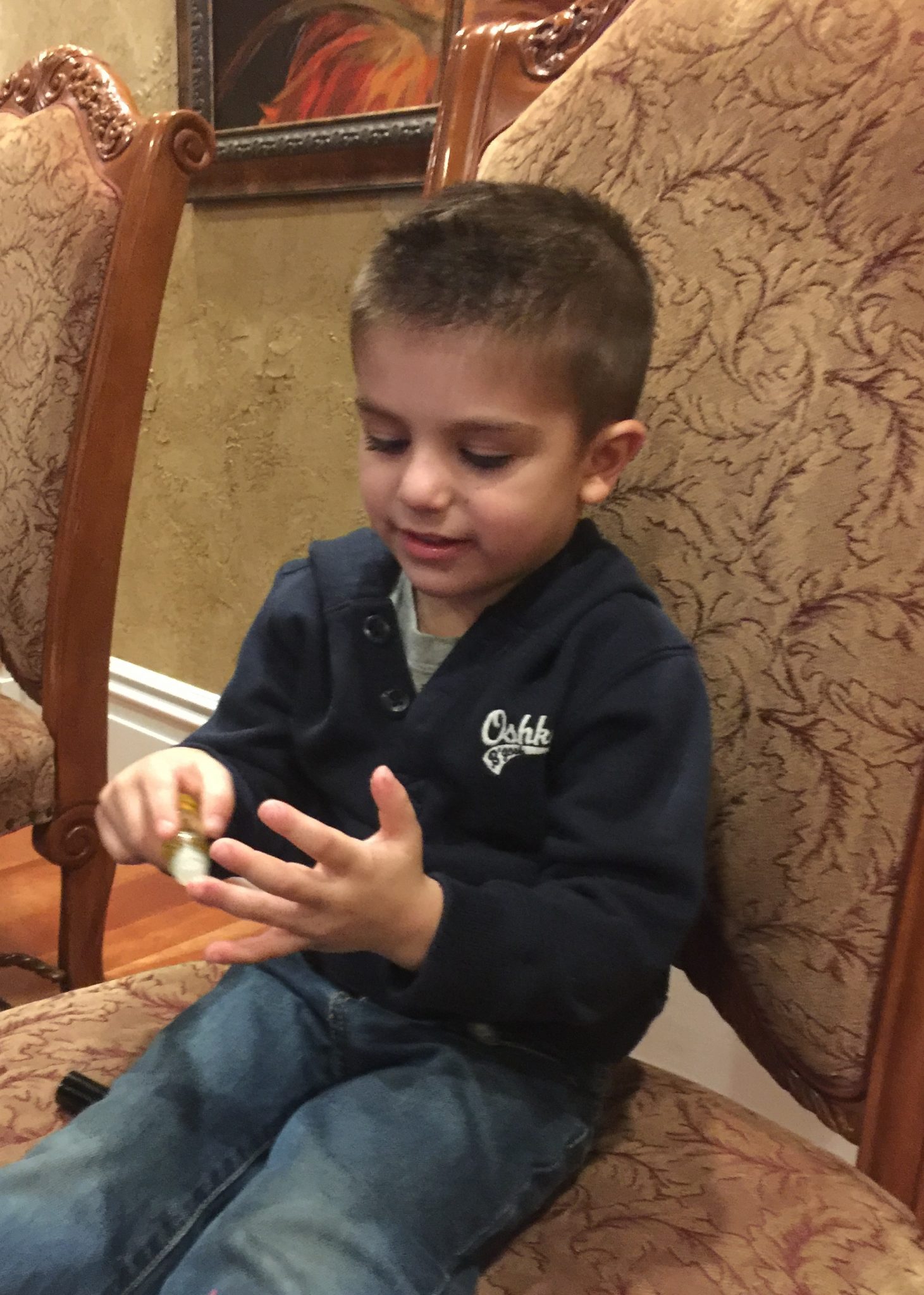 little boy sitting in chair applying essential oils to his fingers