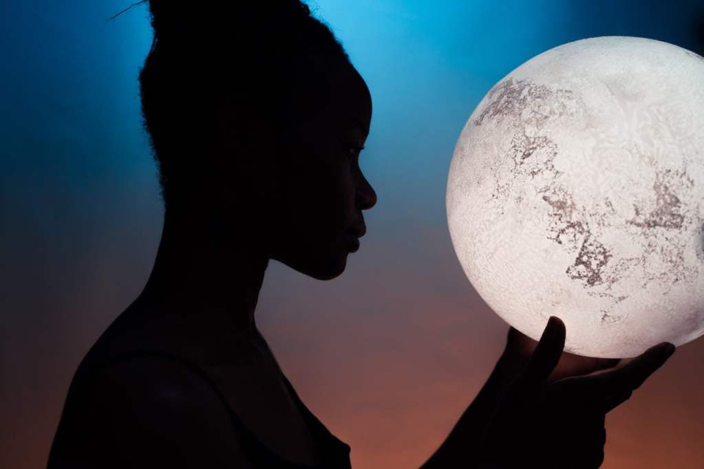 silhouette of woman holding full moon