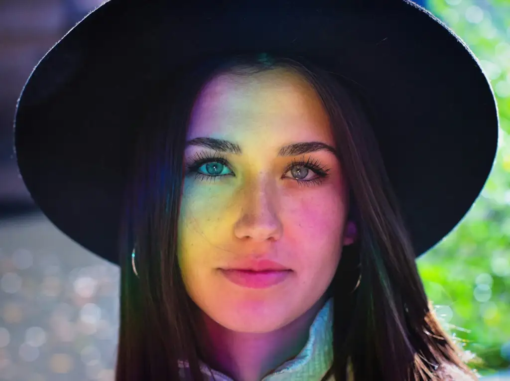 woman wearing hat and standing in front of rainbow