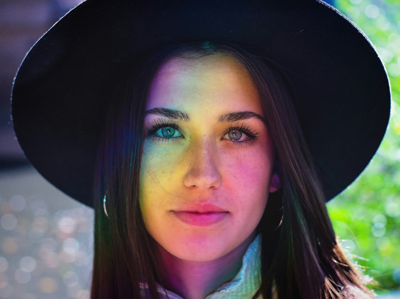 woman wearing hat and standing in front of rainbow