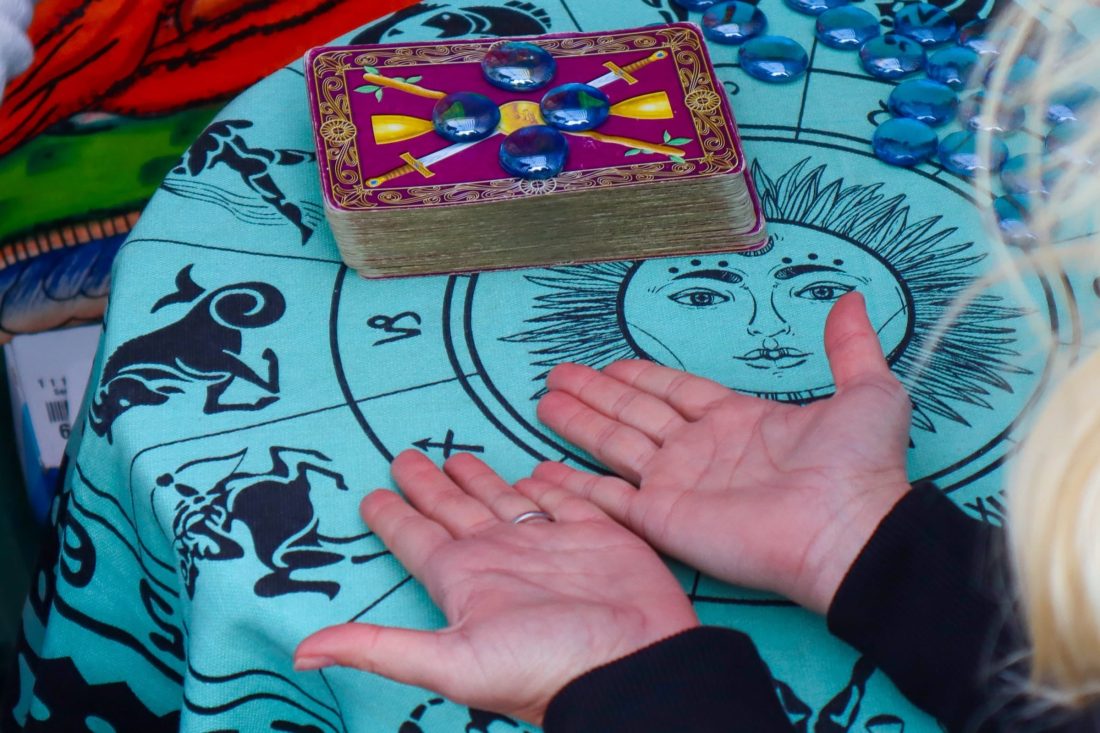 woman's hands with palms face up on a table in front of a deck of tarot cards