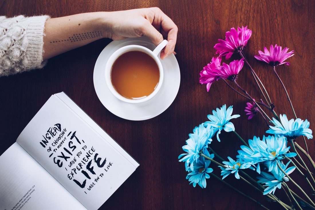 table with open book of quotes, flowers and tea