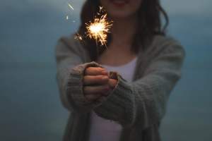 woman in grey sweater holding sparkler