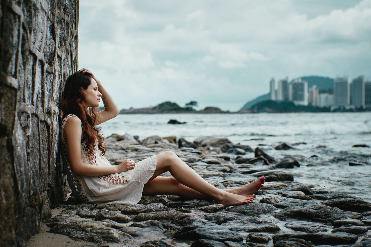 woman leaning on stone wall near water