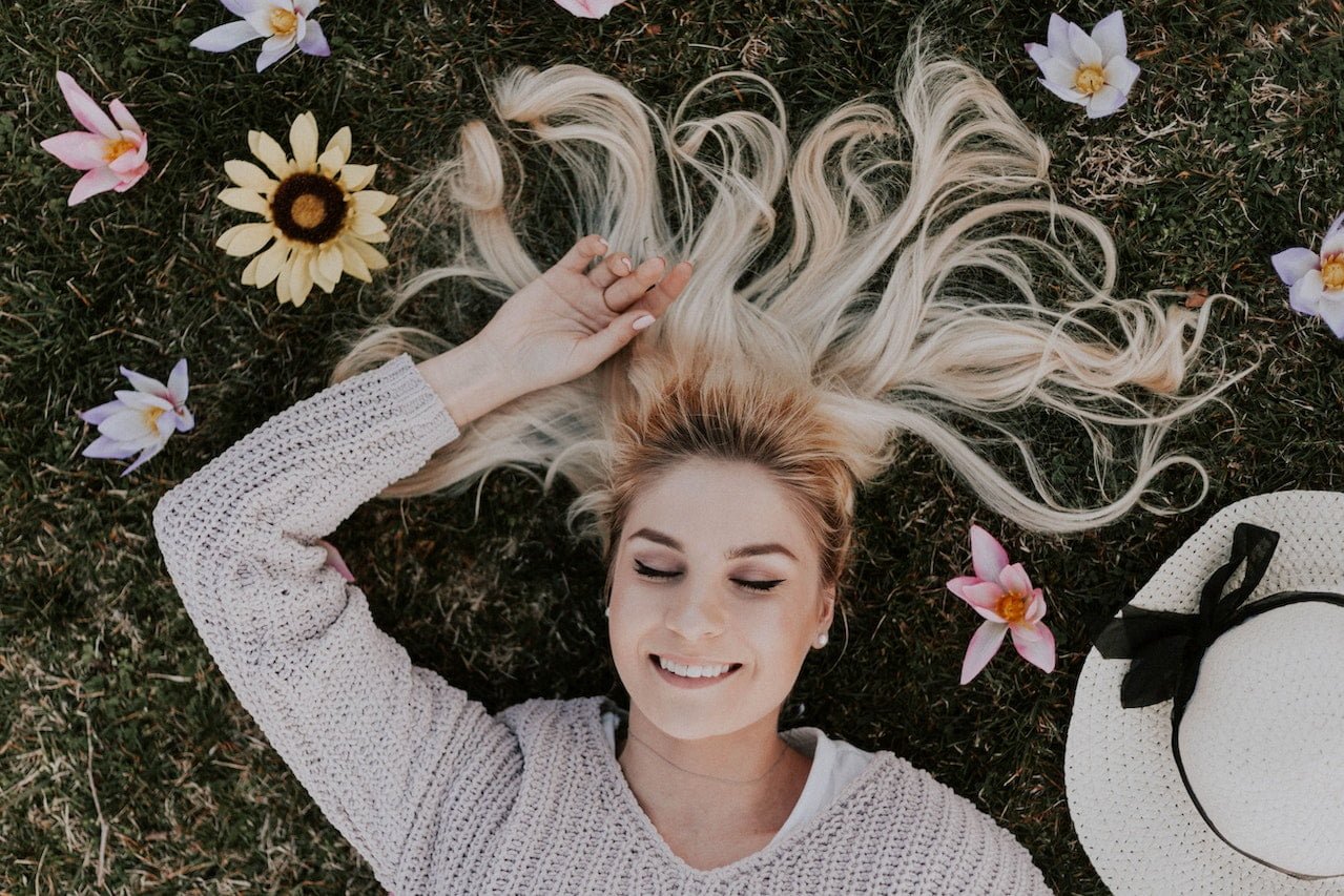 smiling woman lying on flowers and grass