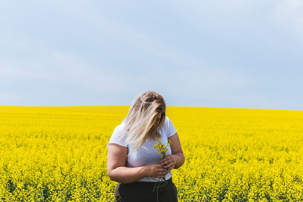 woman standing in field of yellow flowers