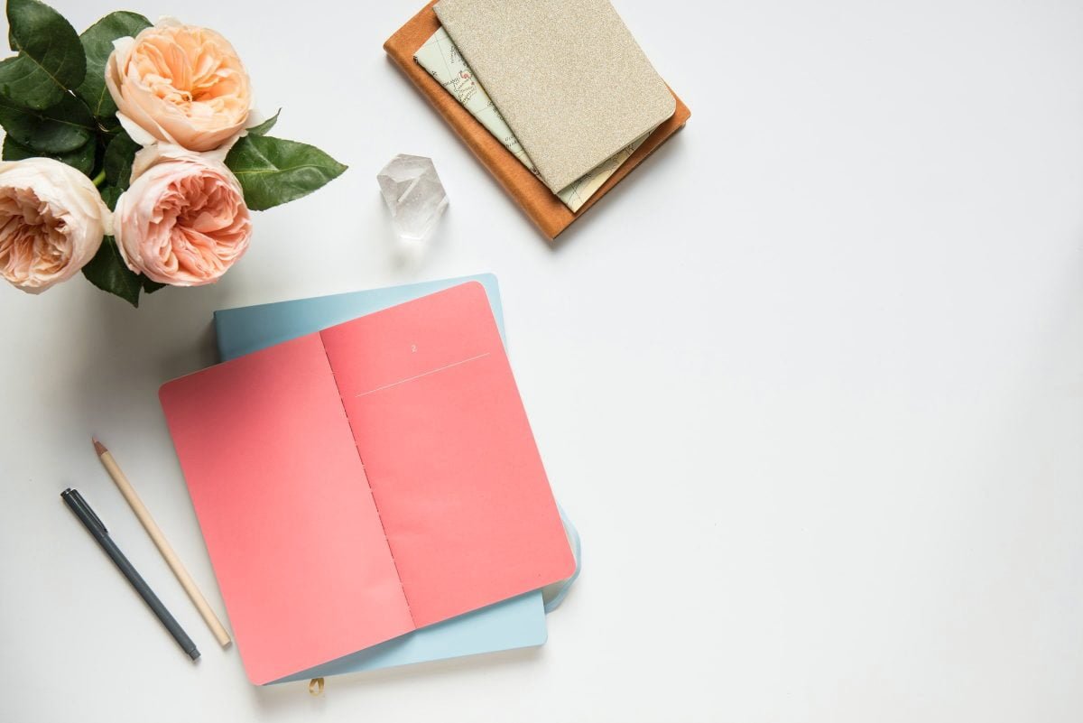 manifesting notebook on table next to vase of flowers