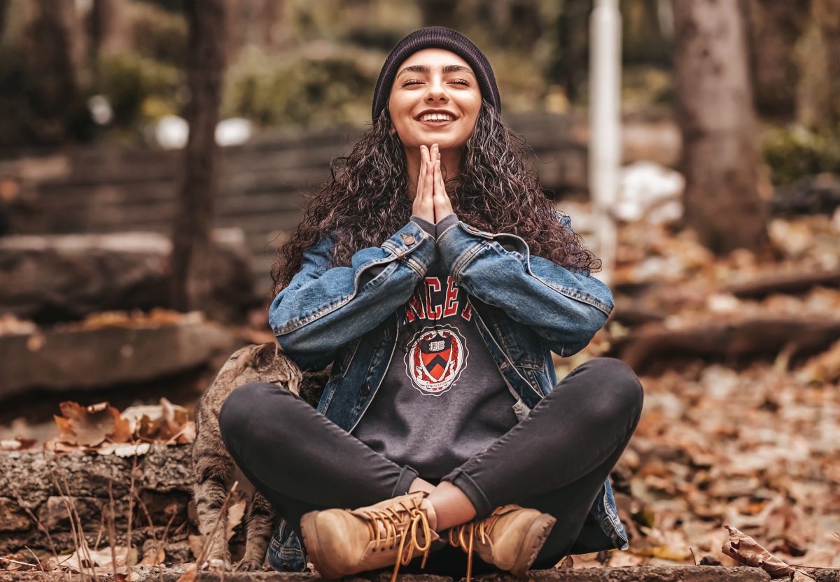 woman cross legged in prayer pose sitting in the woods