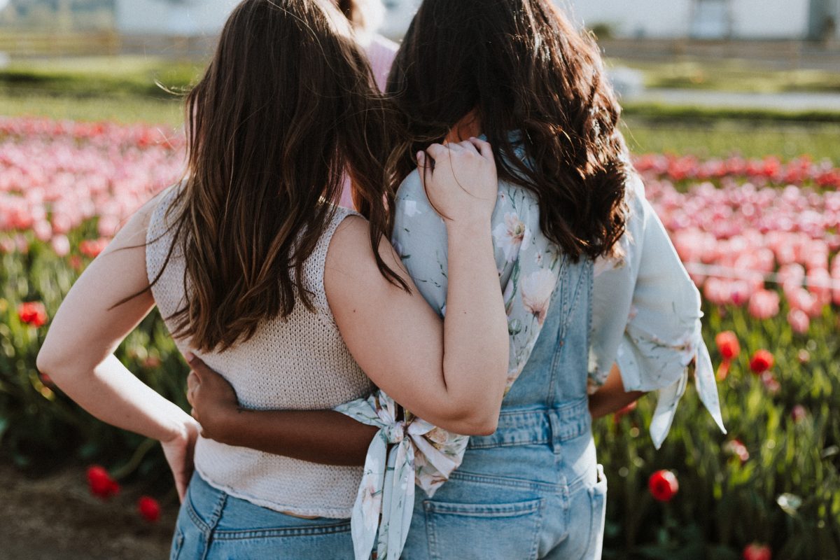 women hugging in flower field