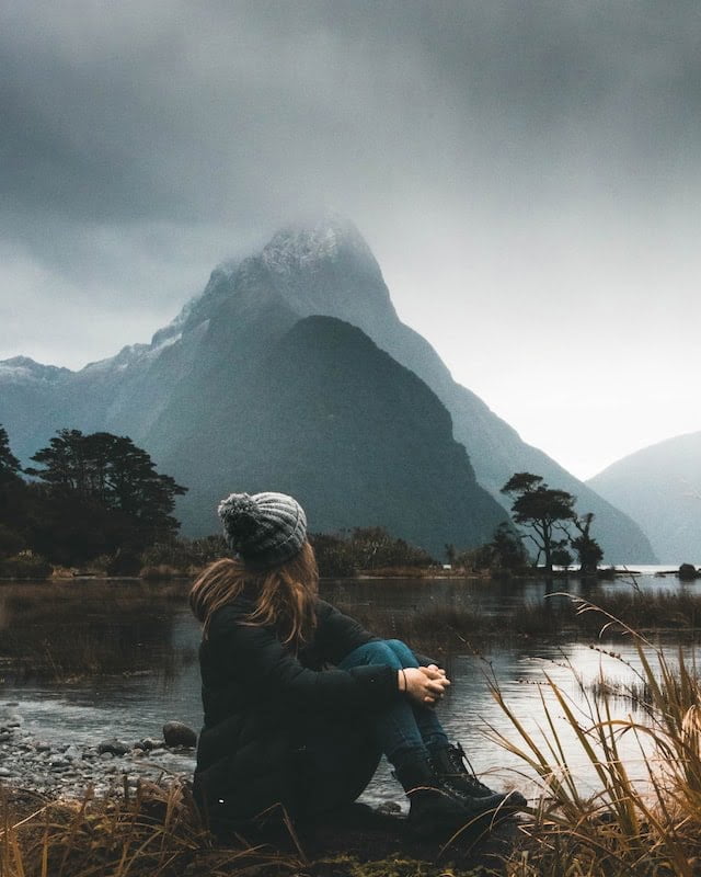 woman sitting on the ground looking at mountains