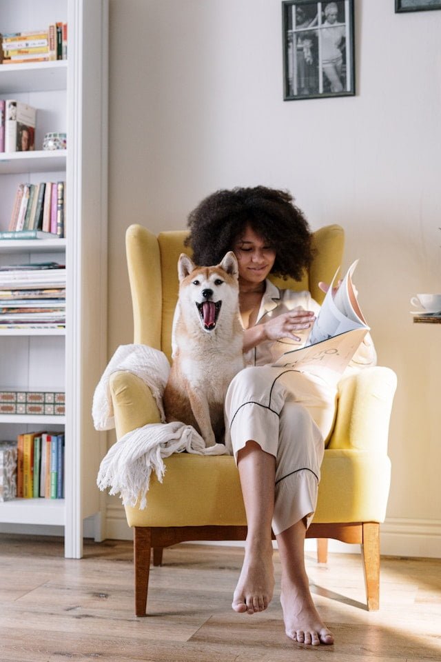 woman reading a book with a dog on her lap