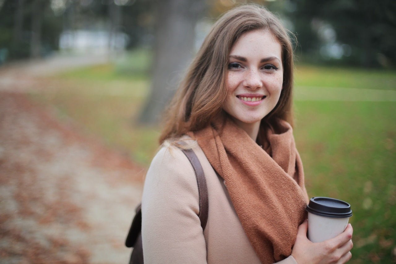 woman in scarf outdoors holding coffee cup