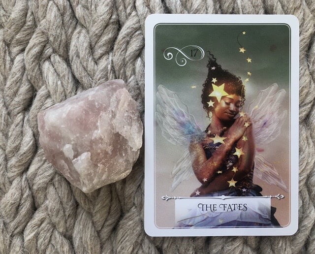 The Fates card from Wisdom of the Oracle next to a piece of rose quartz
