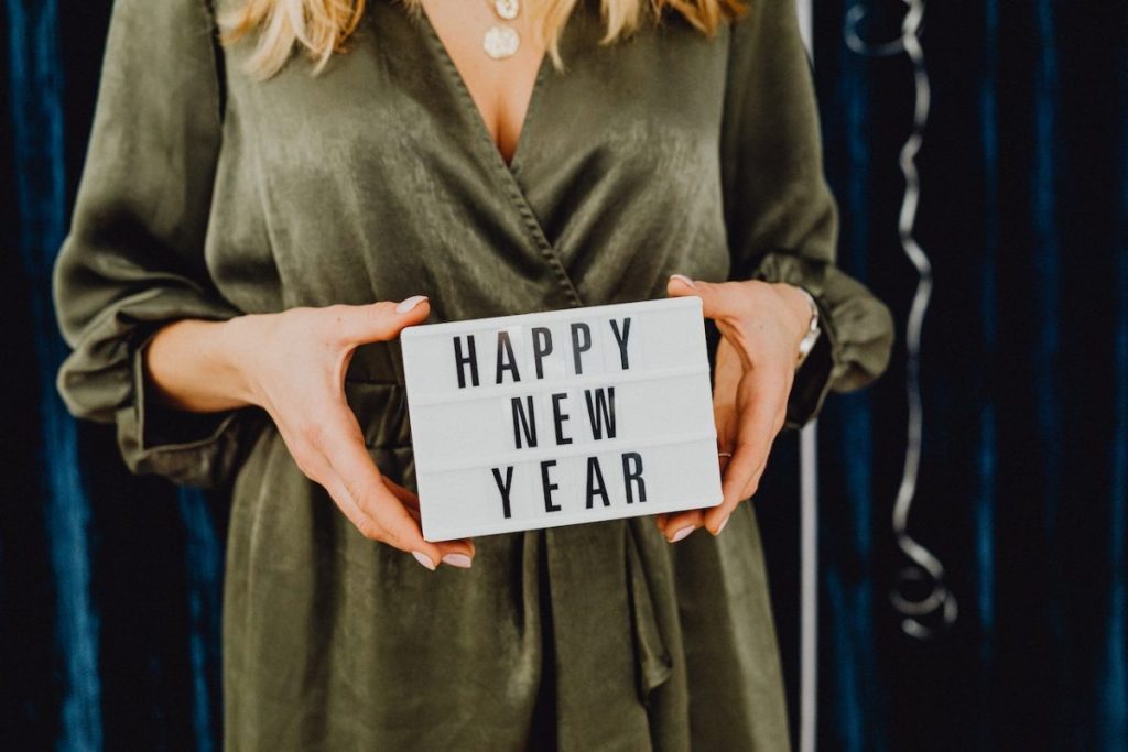 woman wearing green dress holding Happy New Year sign