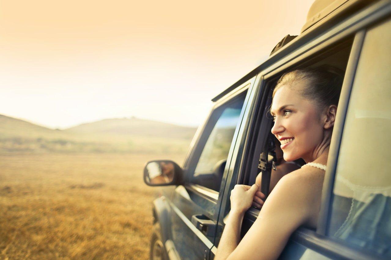 smiling woman sitting in car at sunset