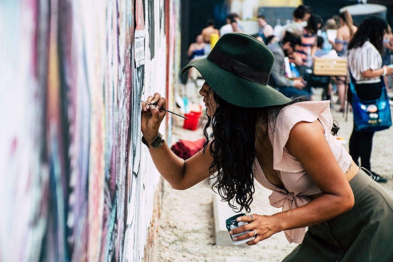 woman painting on outdoor wall
