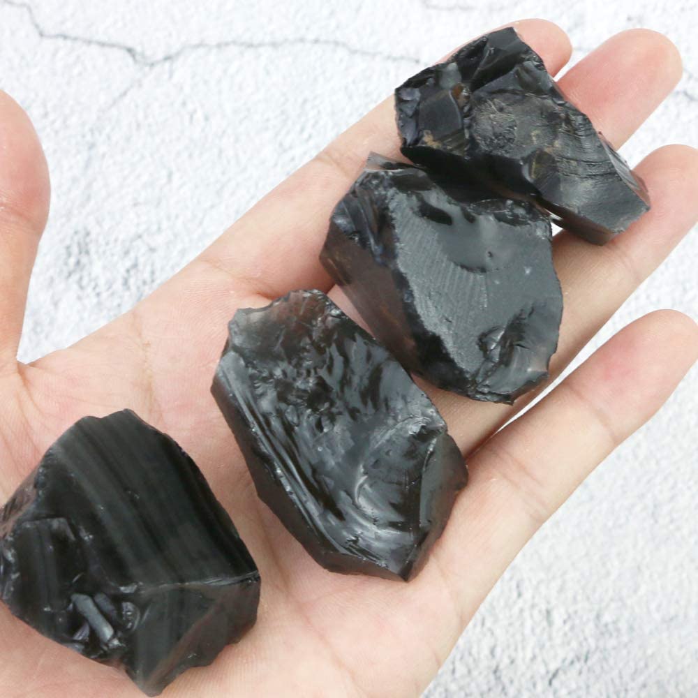 hand holding 4 pieces of black obsidian