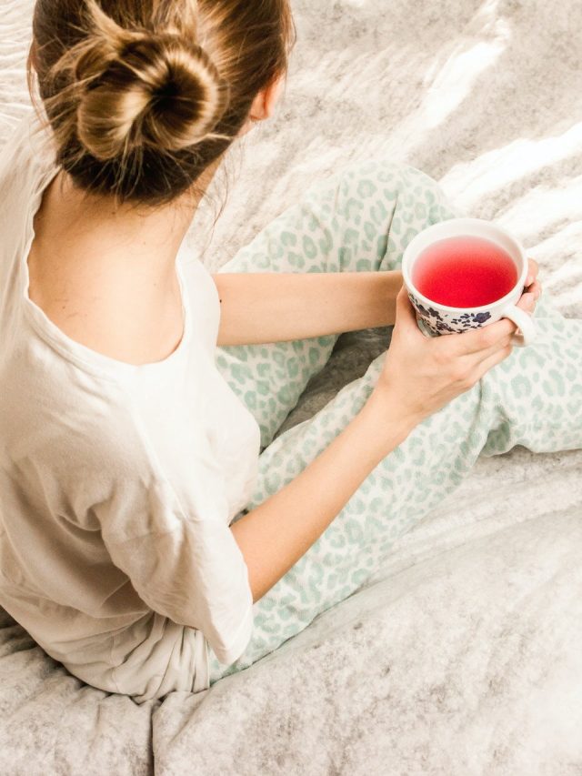 woman sitting on bed drinking a cup of pink tea