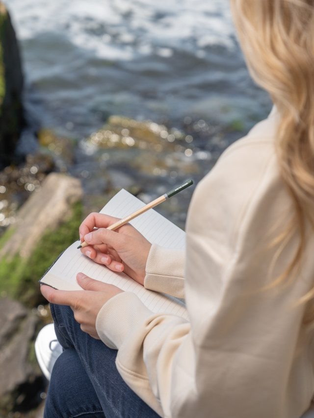 woman journaling outside near a stream