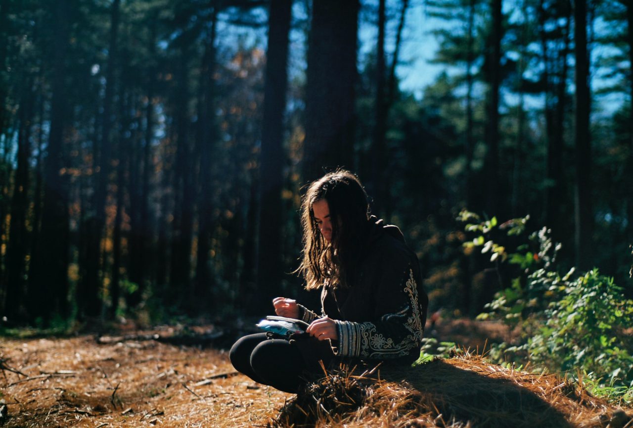 woman in woods writing in journal