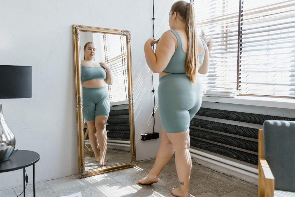 woman in workout clothes looking in mirror