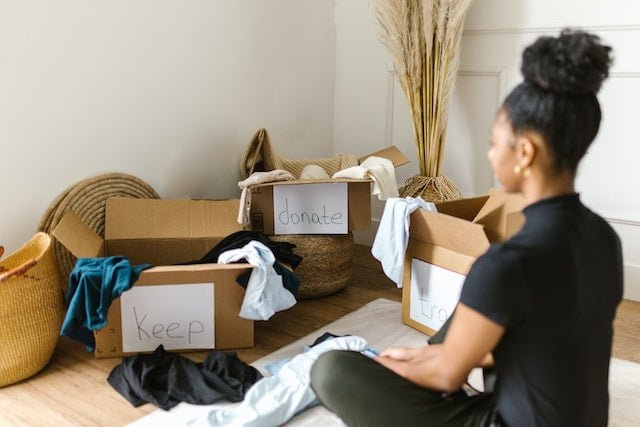 woman sitting in front of cardboard boxes, organizing items