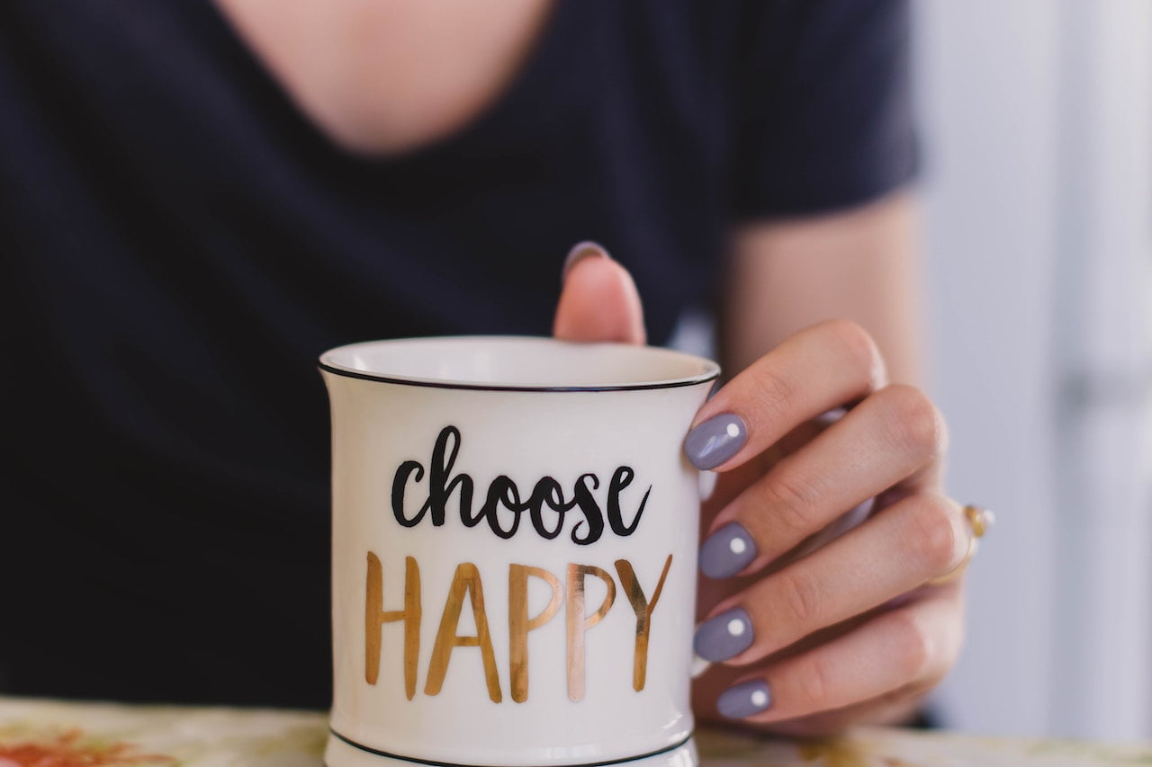 woman holding 'choose happy' coffee mug