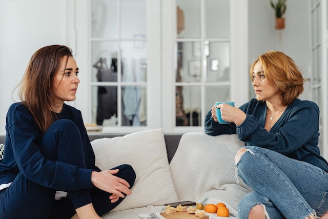two woman drinking tea on a couch
