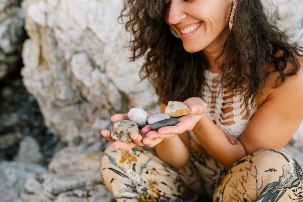 smiling woman with a handful of stones outdoors
