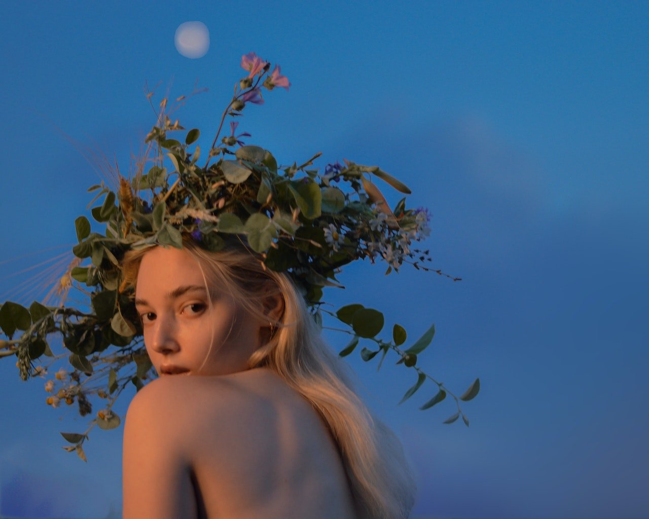 woman wearing garland crown under full moon