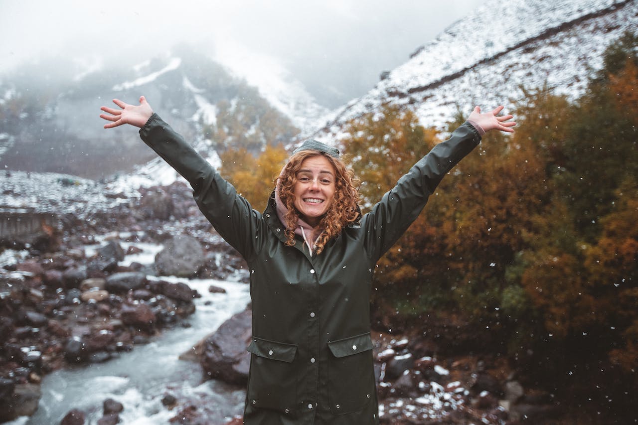 happy woman with arms up in front of mountain