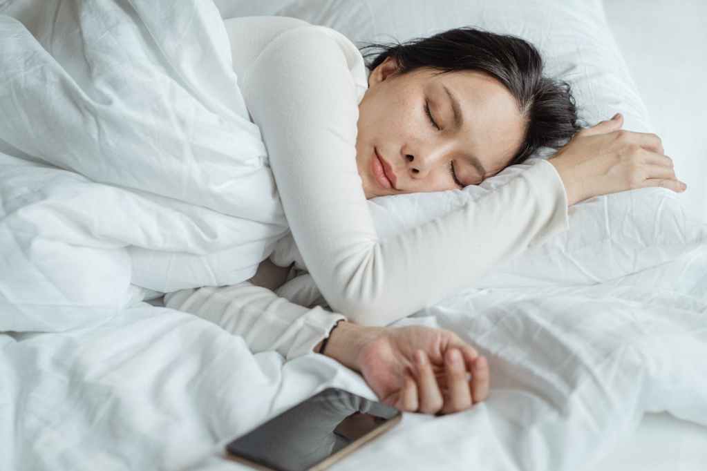 woman sleeping in bed next to her phone