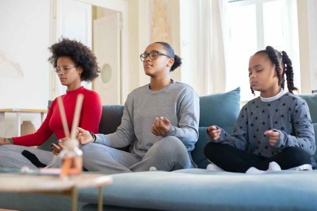 woman and two kids meditating on the couch