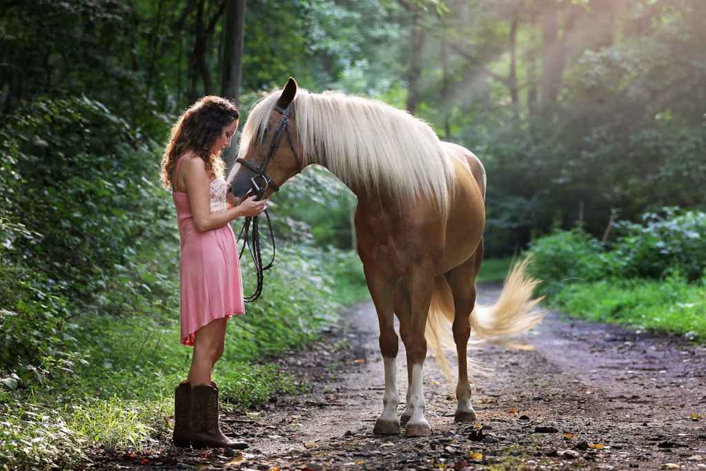 woman standing next to brown horse