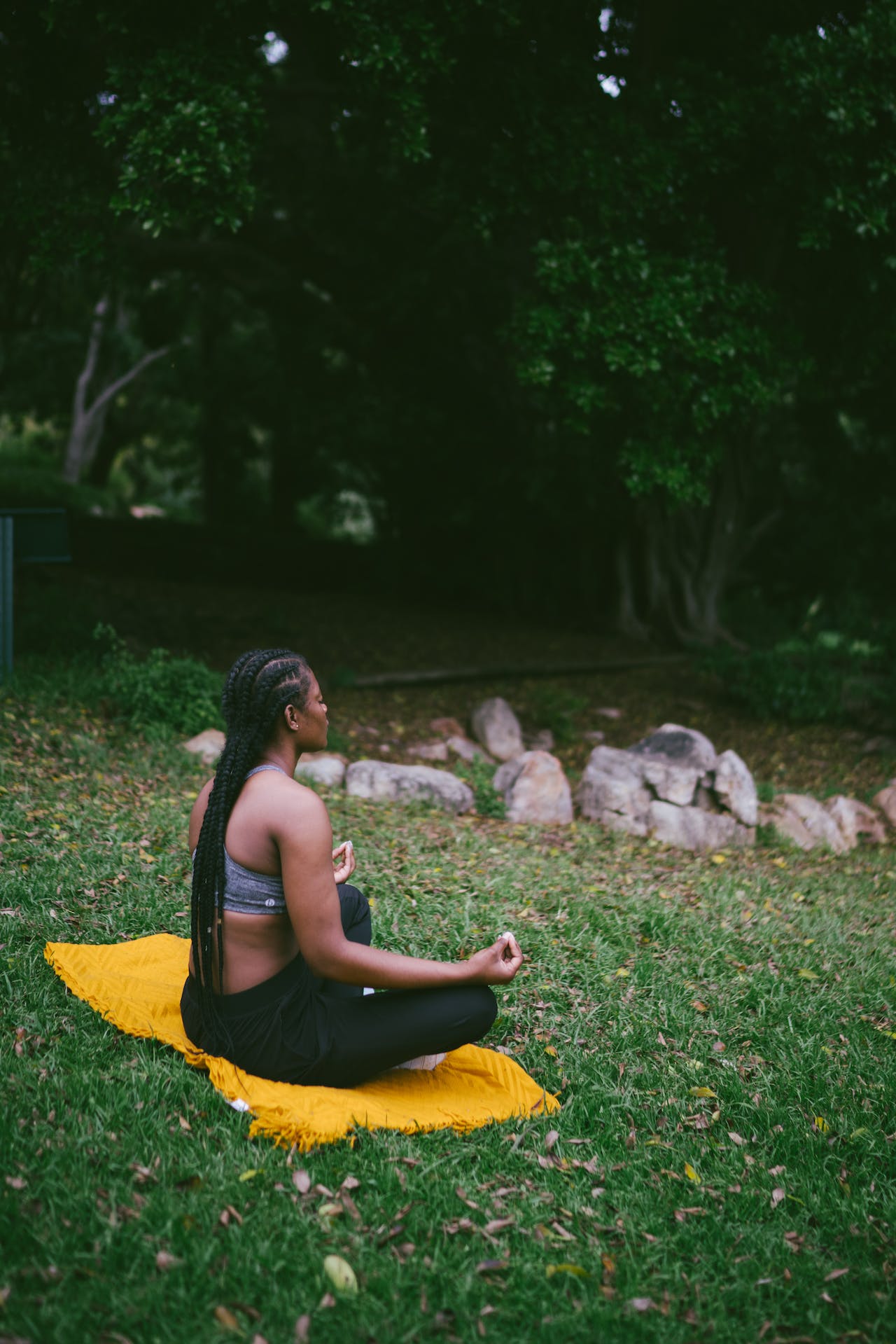 woman meditating outdoors on yellow blanket