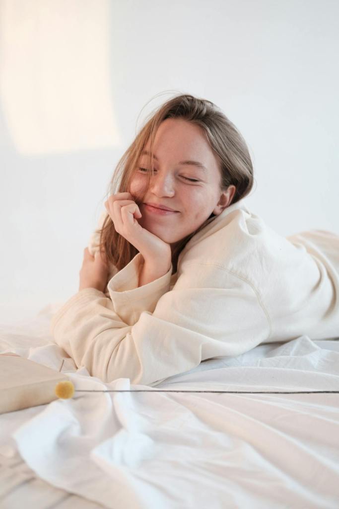 Smiling woman resting on bed with closed eyes
