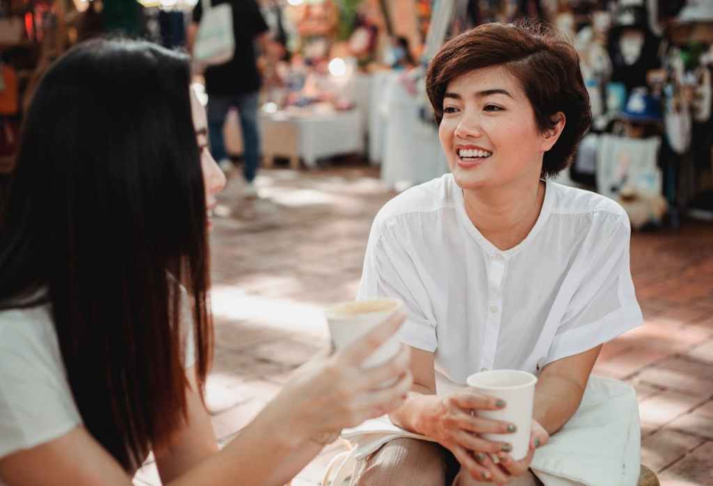 two women talking while drinking coffee