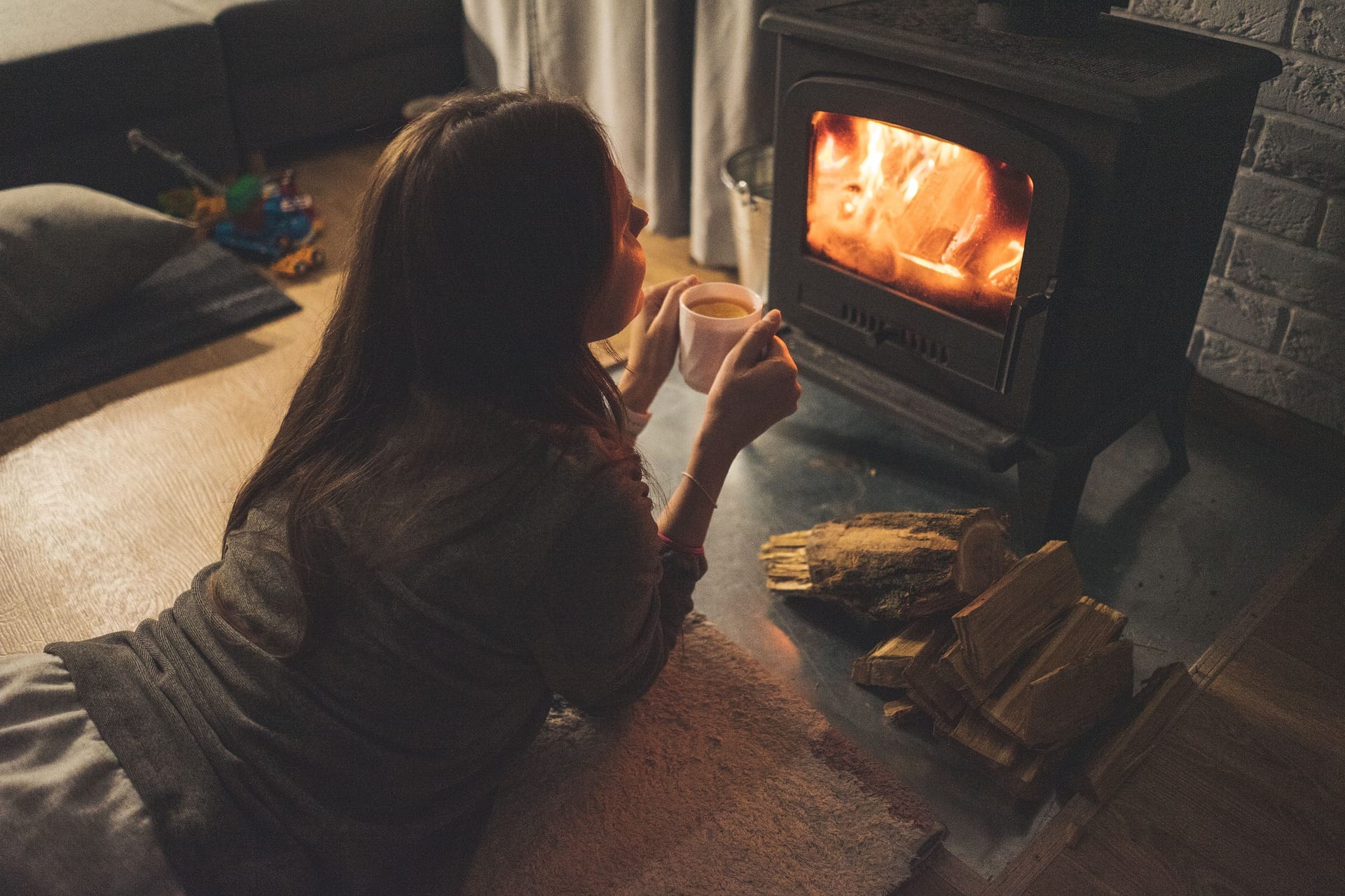 woman holding mug and sitting in front of wood stove